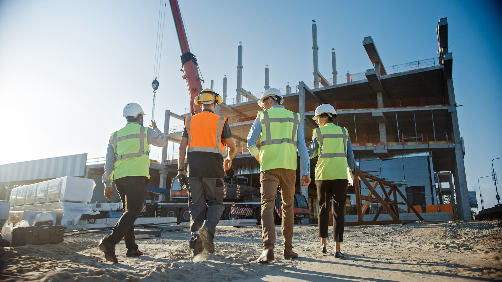 Diverse Team of Specialists Inspect Commercial, Industrial Building Construction Site. Real Estate Project with Civil Engineer, Investor and Worker. In the Background Crane, Skyscraper Formwork Frames. Image: Adobe Stock