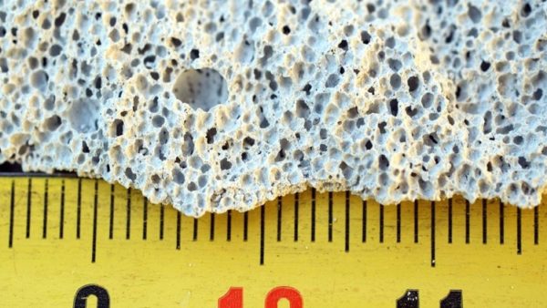 A piece of bubbly concrete with a yellow ruler under it.