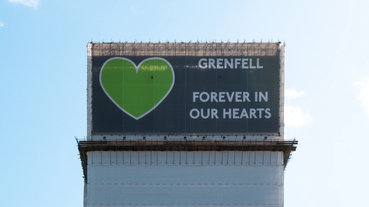 Social Housing Act - The remains of Grenfell Tower, covered in a wrap displaying a green heart with the words: 