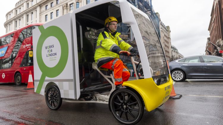 A worker rides the four-wheeled cargo bike on a London street