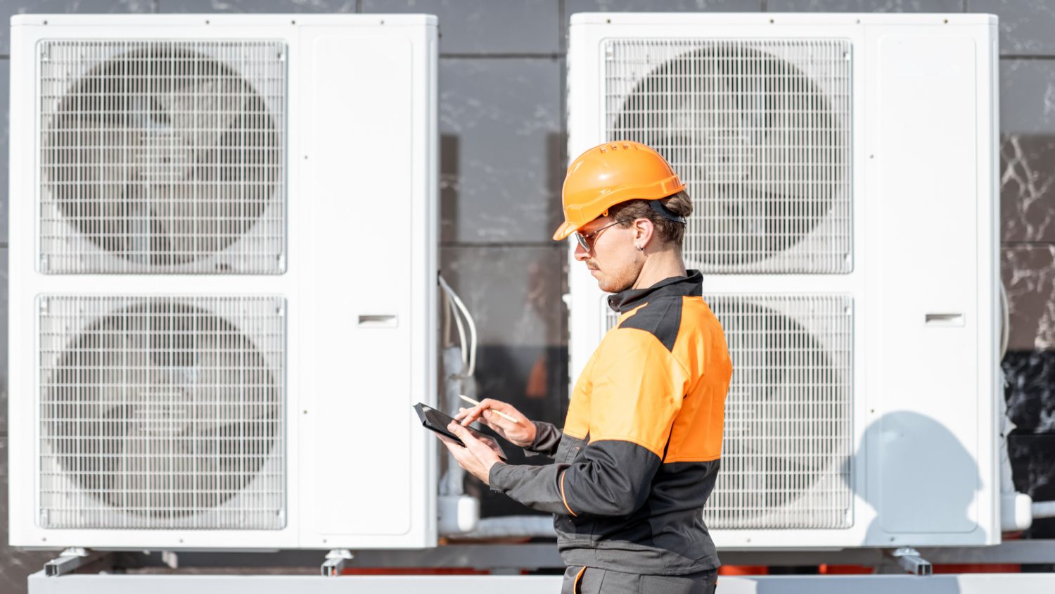 A worker checks a heat pump installation (Photo 163529574 / Air Construction © Rosshelen | Dreamstime.com)