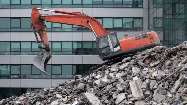Demolition of a building with an orange excavator (Image: Dreamstime)