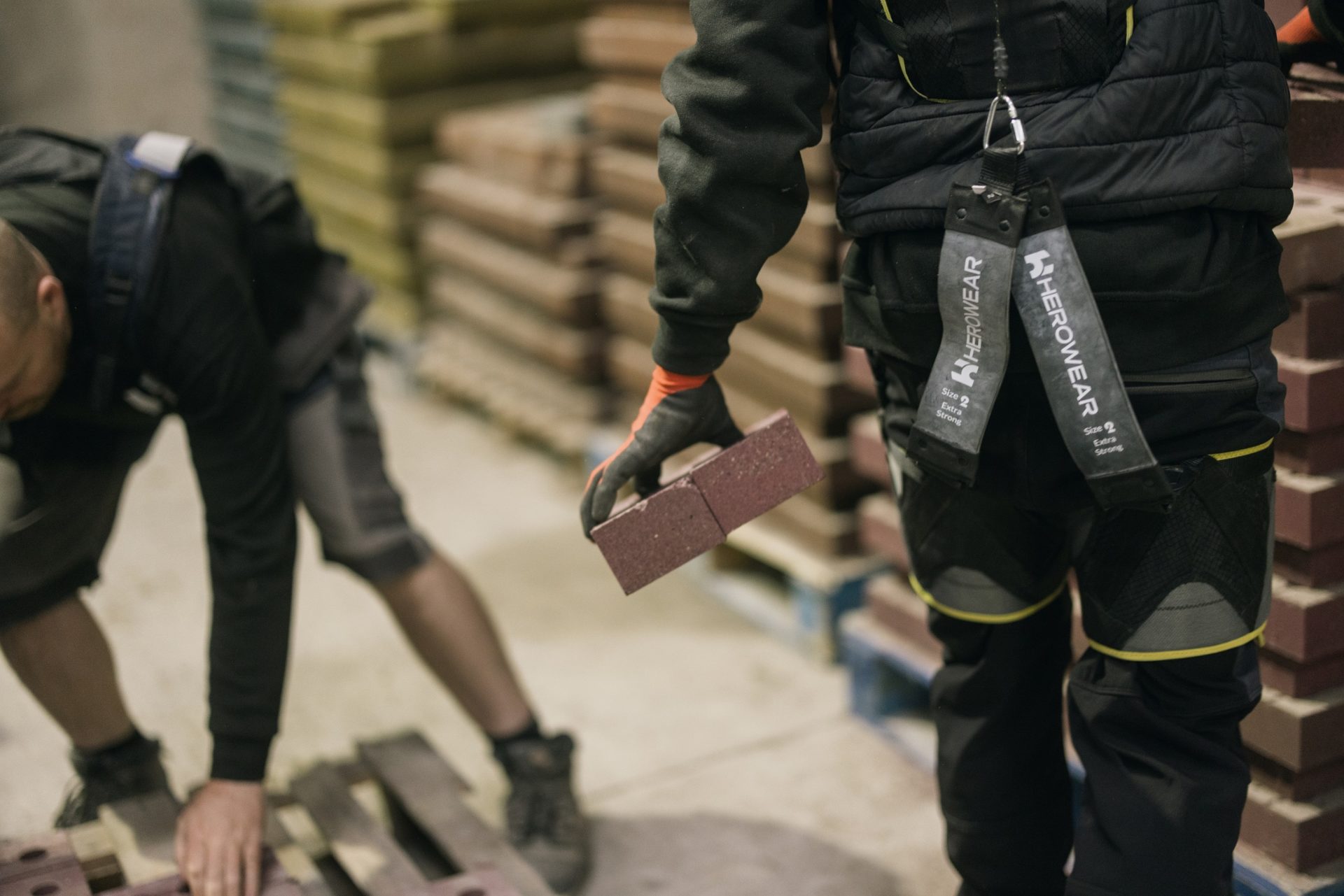 Workers lift bricks using the exoskeletons – Kenoteq is trialling two different models.