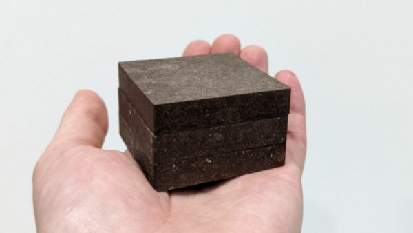 A hand with a black compact cube