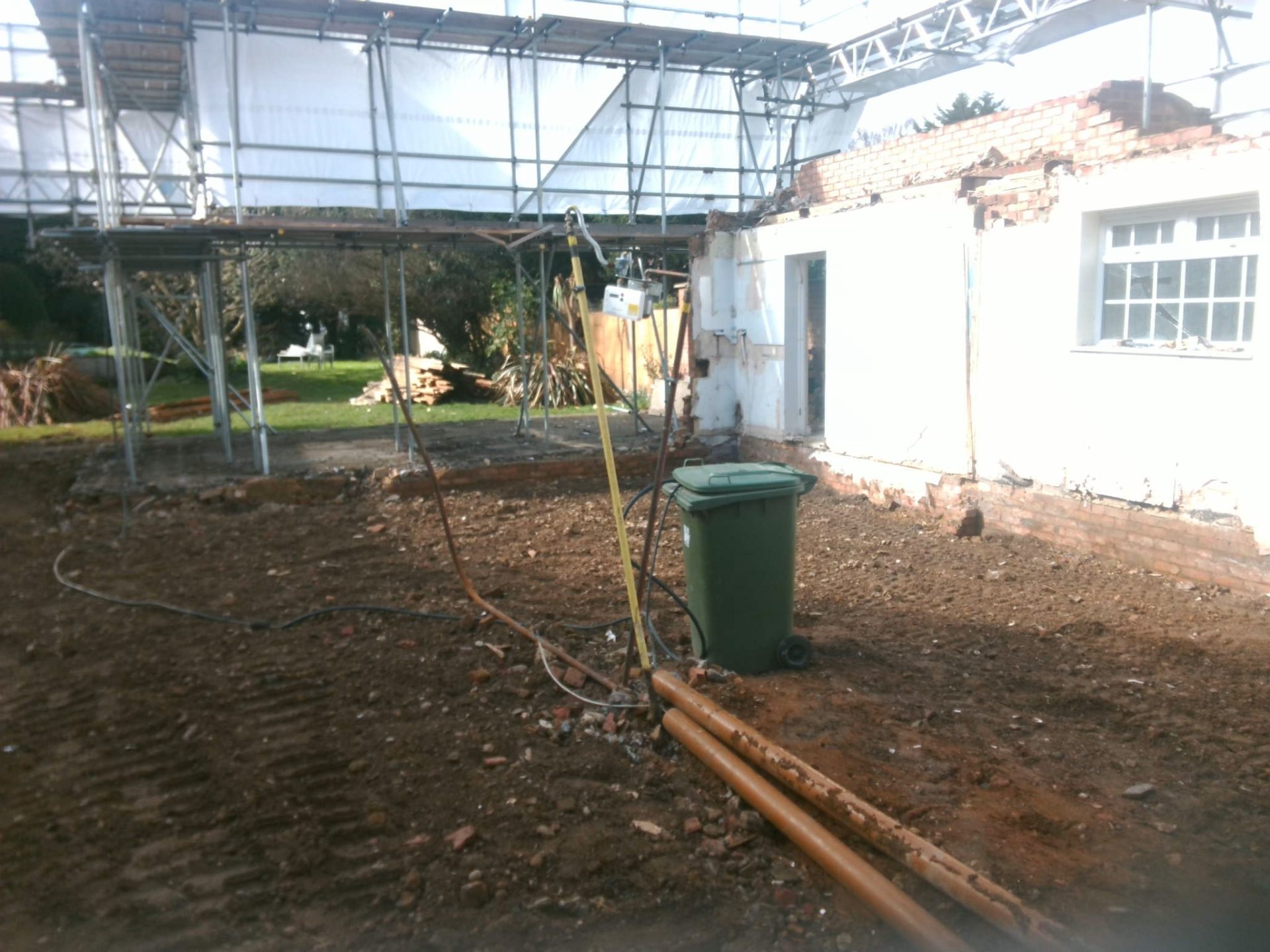 A building site with cables and a wheelie bin.