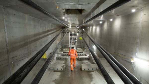 A person in high-vis PPE walking inside a huge concrete tunnel.