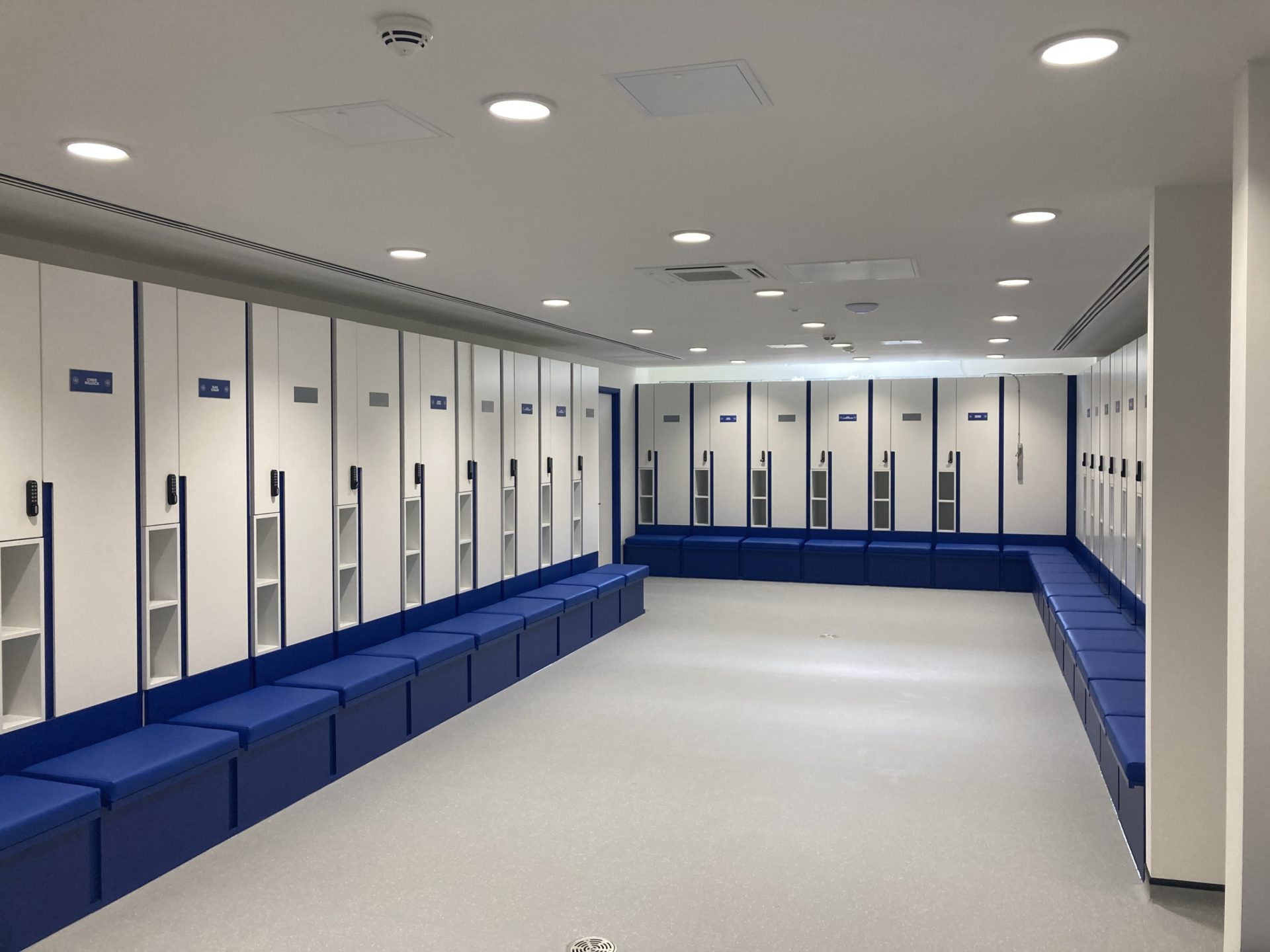 A room with white lockers and blue seats.