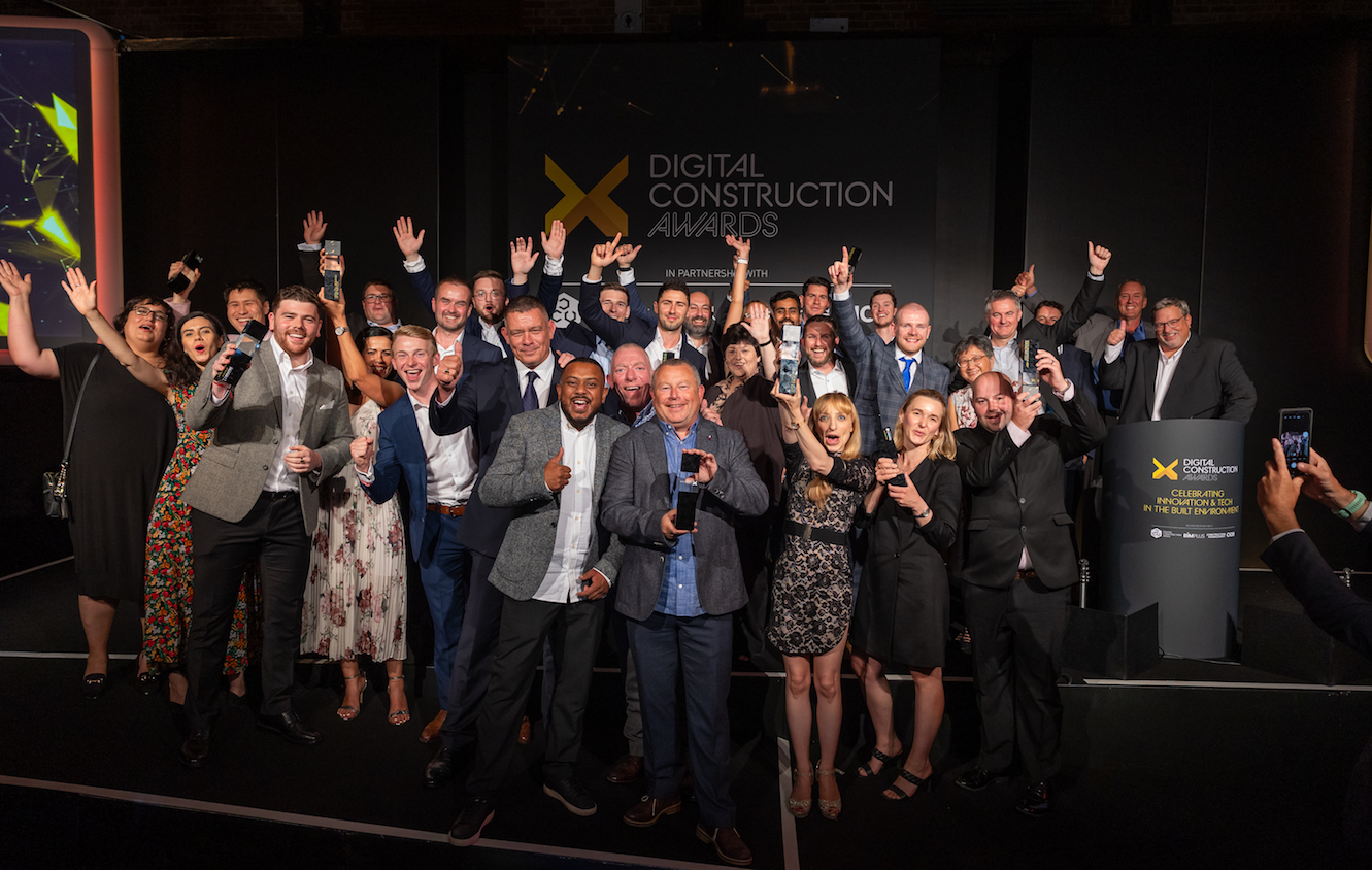 A big group of happy people celebrating. Some have their hands up and some have trophies. Digital Construction Awards