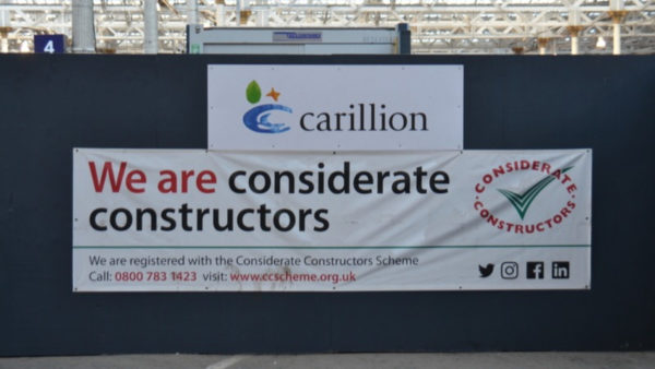 A construction hoarding with two banners, one that says Carillion and another that says we are considerate constructors.