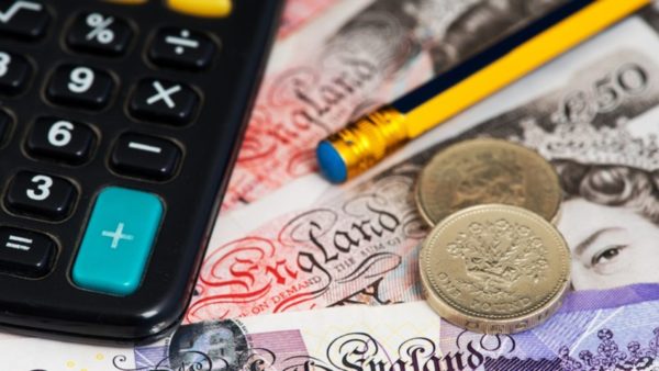 British pound notes and coins, a calculator and a pencil.