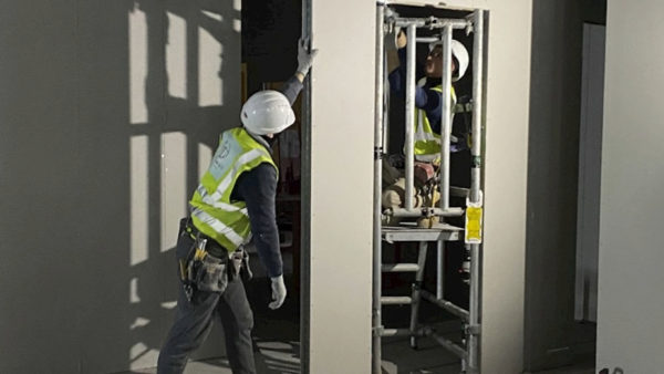 Workers installing plasterboard.