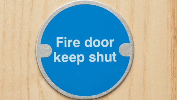A blue round sign that says 'fire door keep shut' on a door.