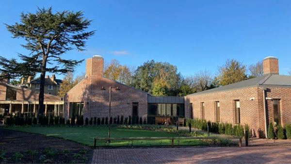 View of a a low brick building with a garden at the front.