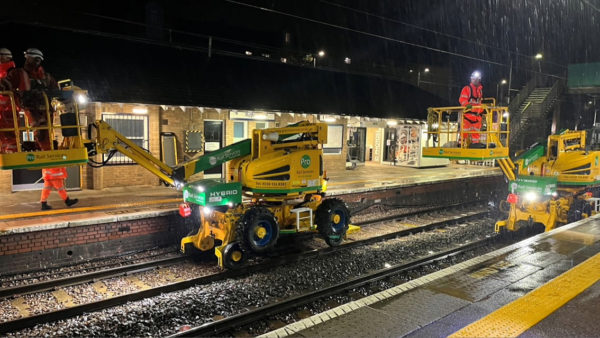 A rail station with a machine on the tracks doing maintainance works.