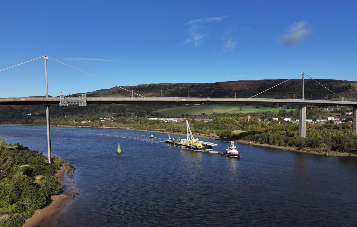 View of a large boat on a river carrying a bridge span.