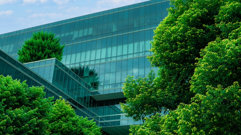A moder glass office with trees.
