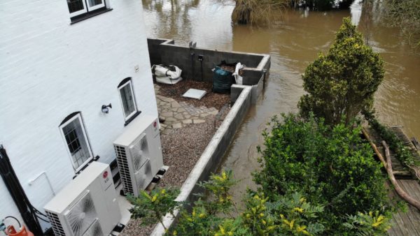 A defence around a house. Outside it, a river has flooded.