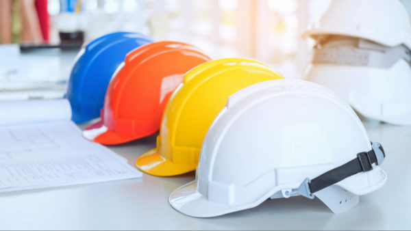 A row of four hard hat helmets of different colours on a table.