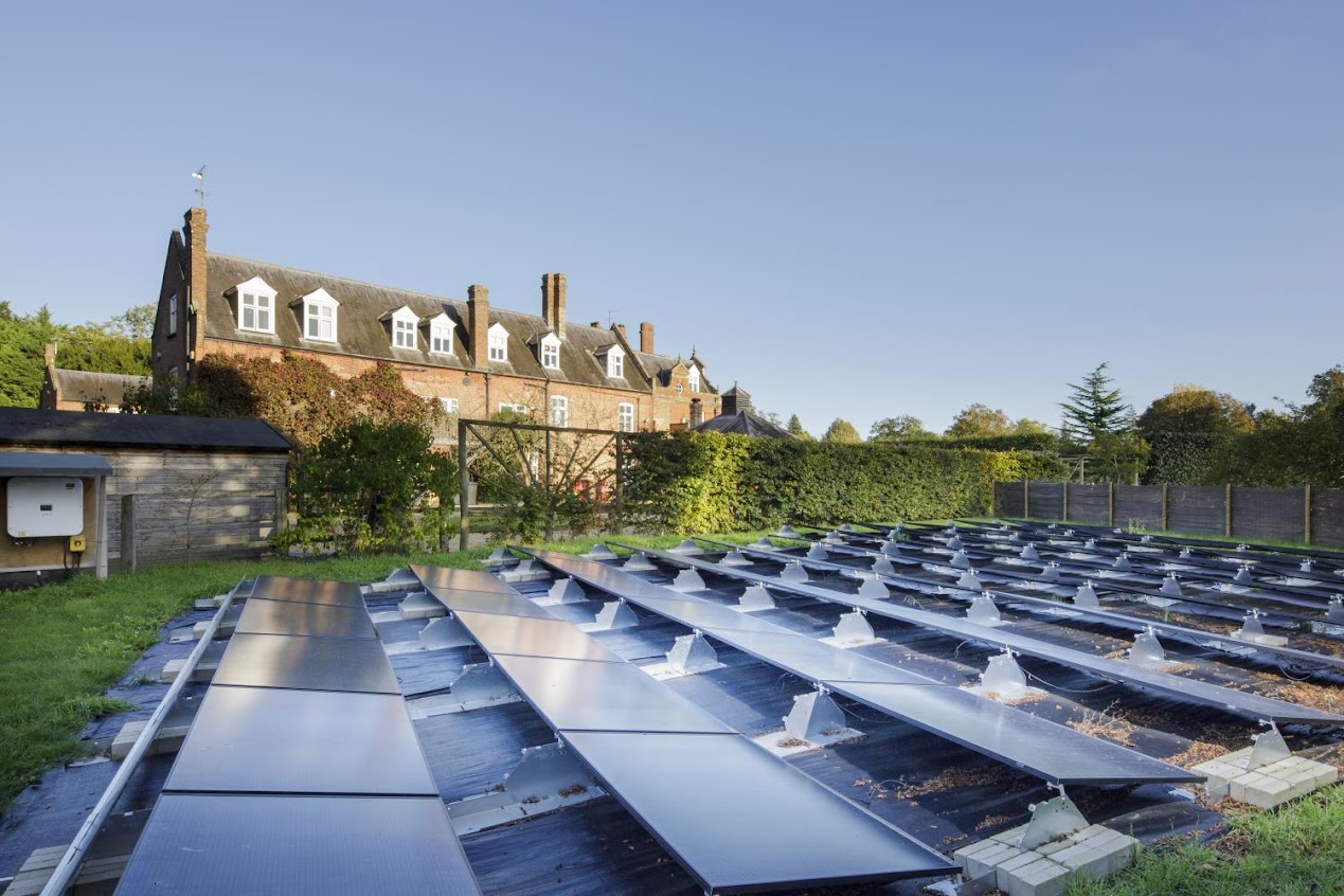 Exterior general view showing solar panels with beech screen and west wing of Chippenham Hall.