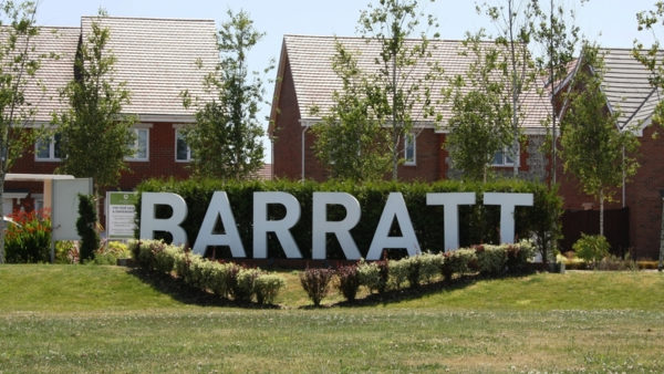 A large white Barratt sign in front of a section of a new housing development in the UK. The housebuilder has set aside £192m to deal with legacy building safety defects.