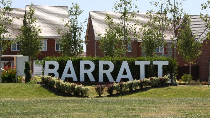 Barratt Homes England - A large white Barratt sign in front of a section of a new housing development in the UK. The housebuilder has set aside £192m to deal with legacy building safety defects.