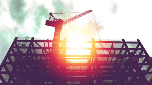 Silhouette of crane in building construction site with sunlight and dark sky