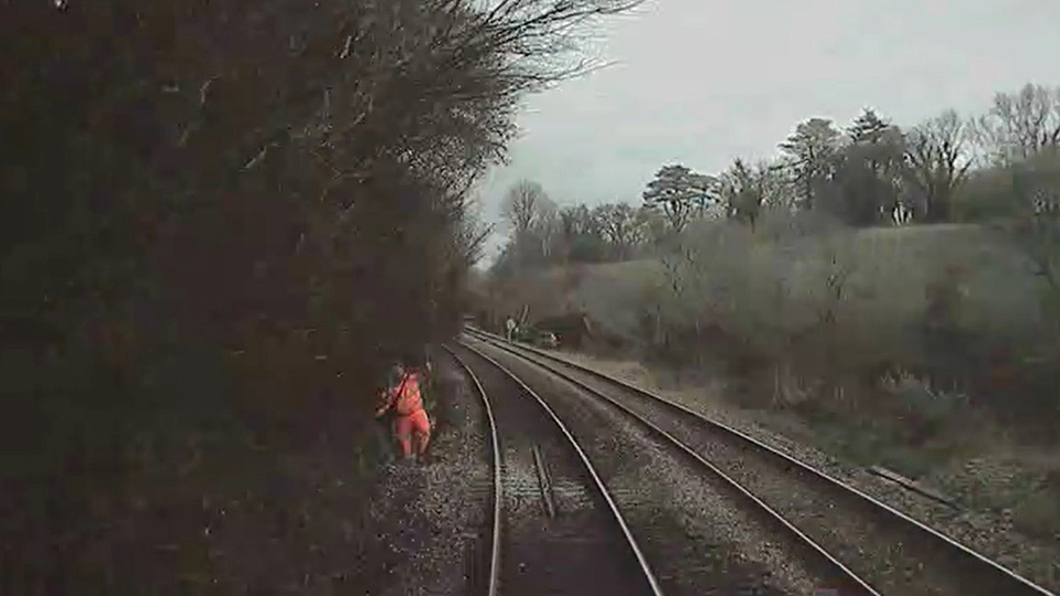 Forward-facing CCTV showing the controller of site safety in the up line cess as the train approaches