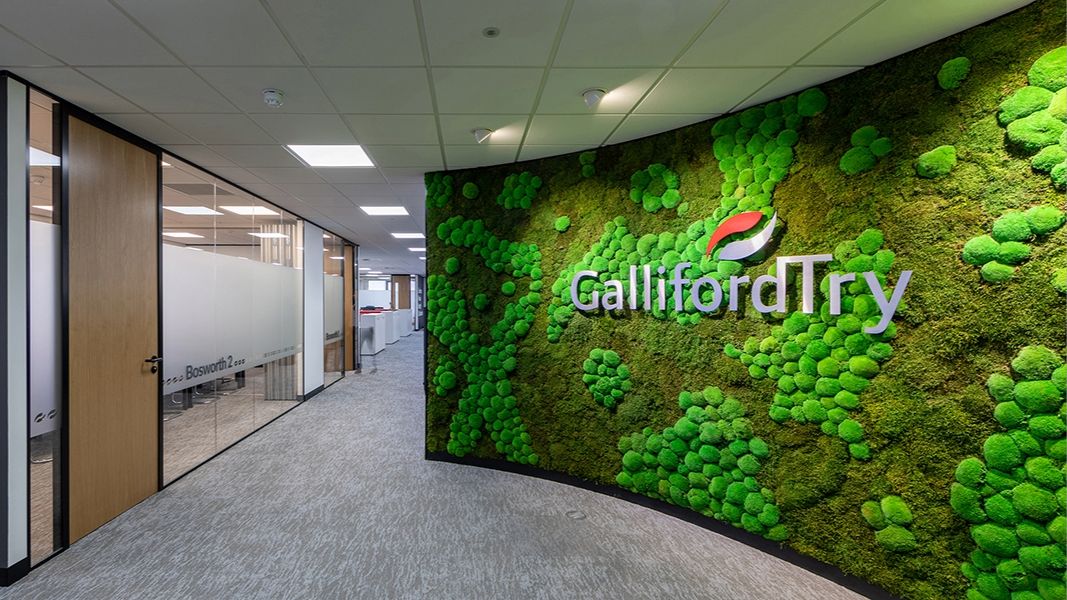 An office with a green wall with Galliford Try's logo. The contractor has published a plan to become net zero by 2045.