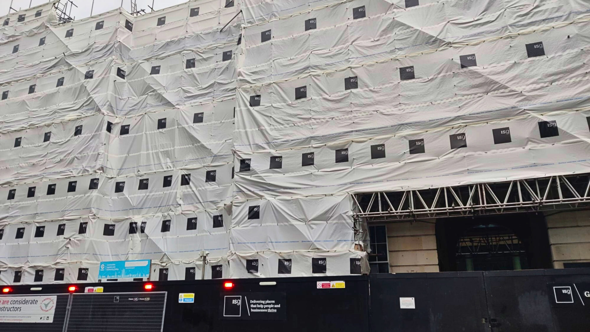 Outside of a closed ISG project with white scaffold sheeting and black hoarding with ISG signagne. Lawyers share five considerations for subcontractors worried about the impact that ISG's collapse might have on them.