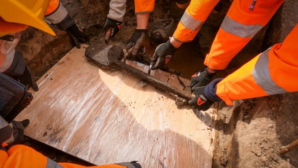 Archaeologists carefully life the fragile spade from the ground on to a board to be sent back to Wessex Archaeology’s laboratory for conservation - one of Britain's oldest wooden tools has been found at a Kier construction site.