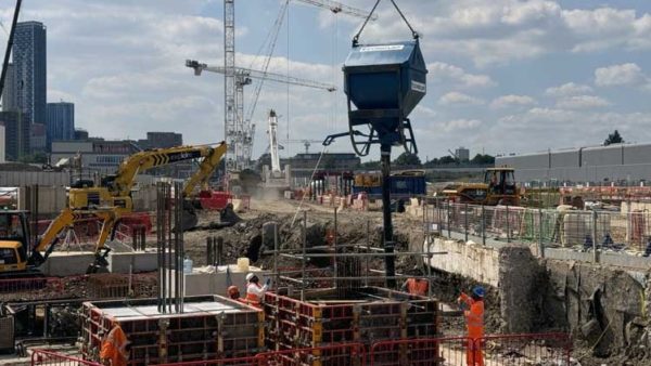 A concrete skip suspended above a construction site - Balfour Beatty, Laing O'Rourke and Conquip have trial new equipment to make this operation safer.