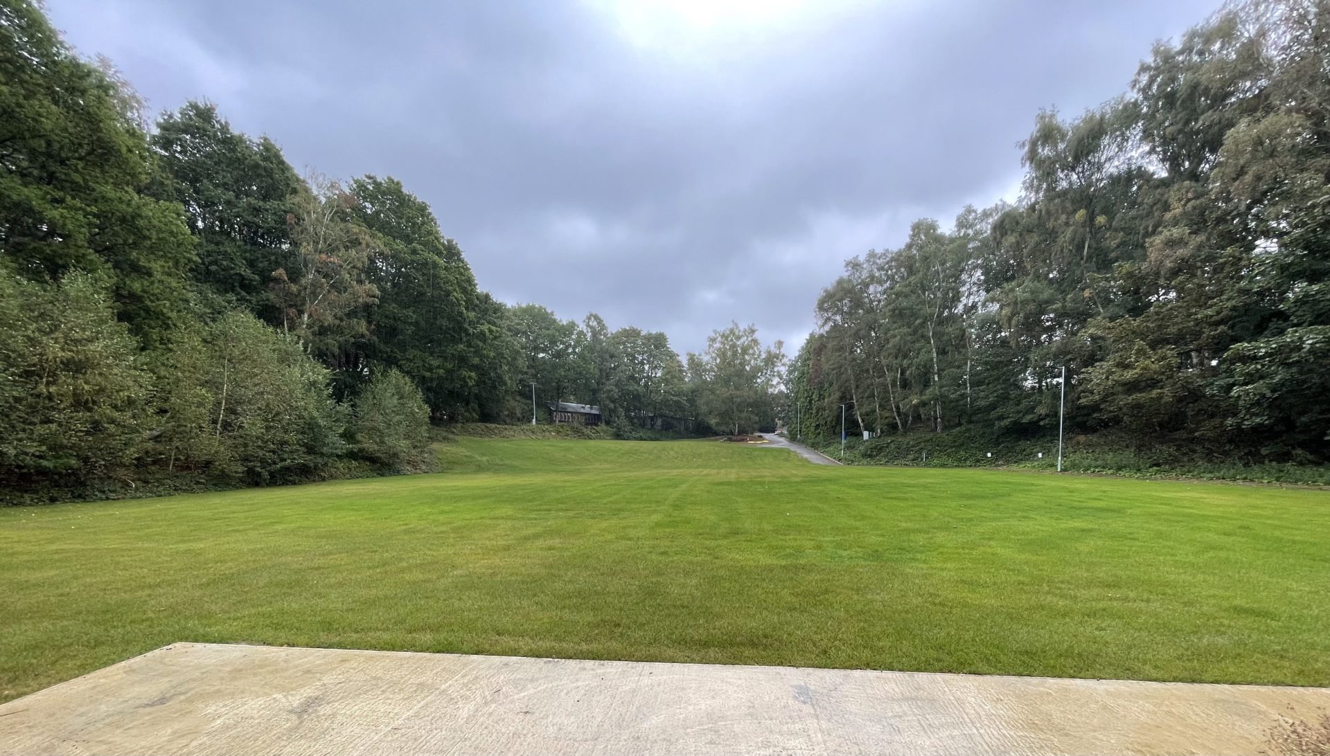 The restored site now looks like a green field with trees surrounding it.