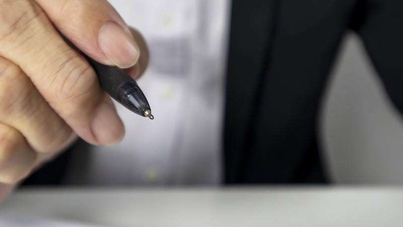 A hand with a pen about to sign a contract on paper - CLC has raised concerns about clients in construction amending industry-approved forms of contract to introduce terms that are 