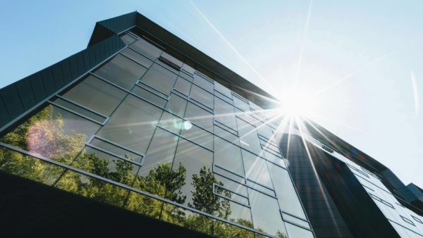 A glass building seen from the ground level with the sun reflecting on it - CIOB has signed up to #GreenSkillsAtCop campaign