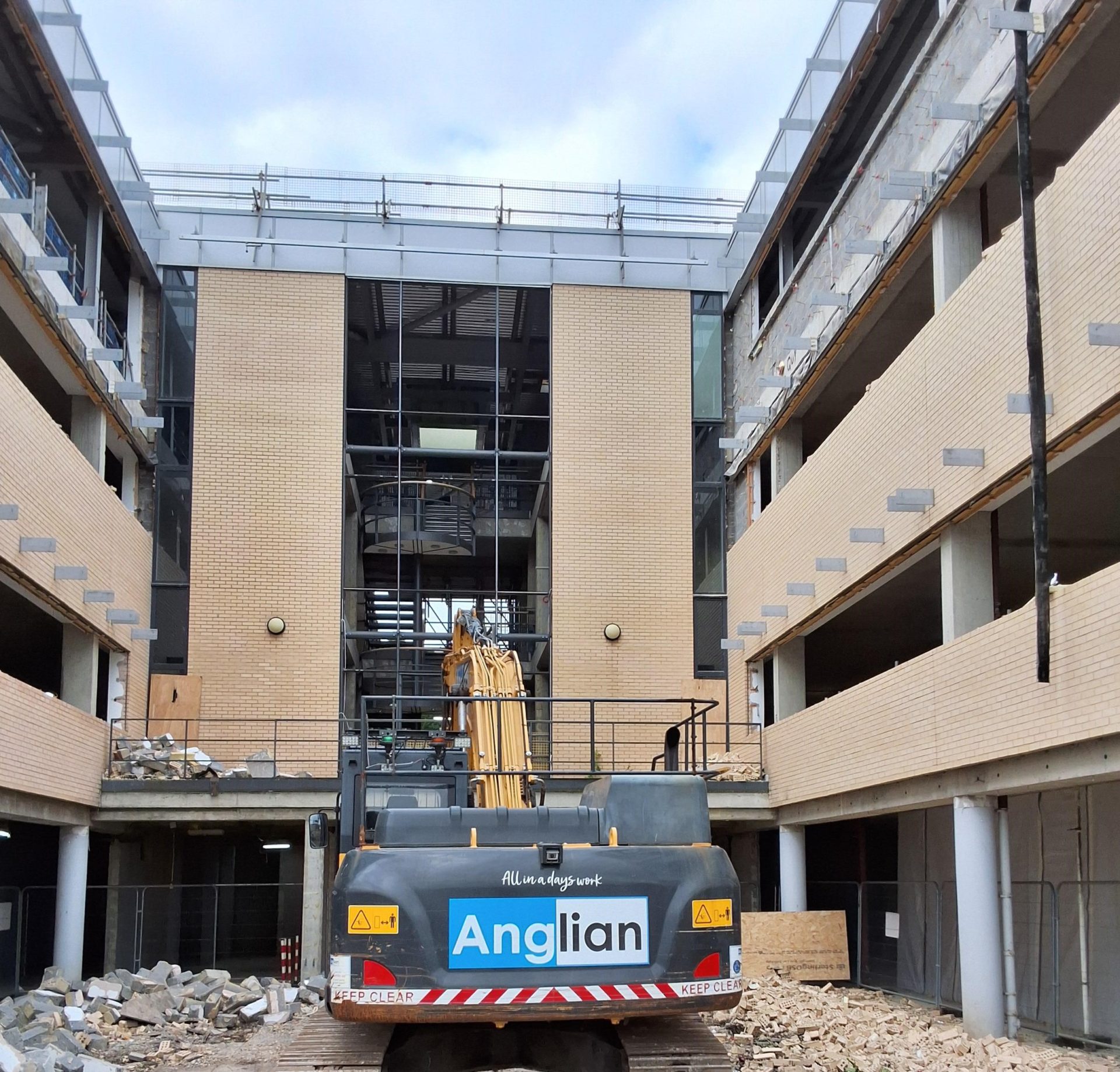 A construction digger demolishing walls in a construction site - Anglian Demo is helping transform offices in Wates project in Cambridge