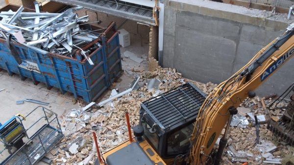 A construction digger demolishing walls in a construction site - Anglian Demo is helping transform offices in Wates project in Cambridge