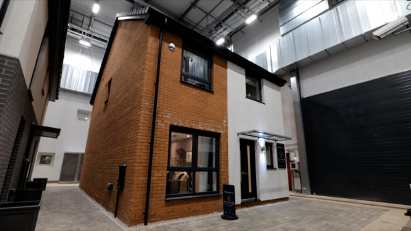 The Bellway Future Home research facility showing a semidetached house made of brick inside a big research facility.