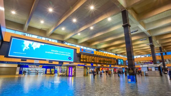 Concourse of London Euston station with a few passengers in the background and big screens showing train times and adverts. The rail minister has said the station is no longer in fit condition.