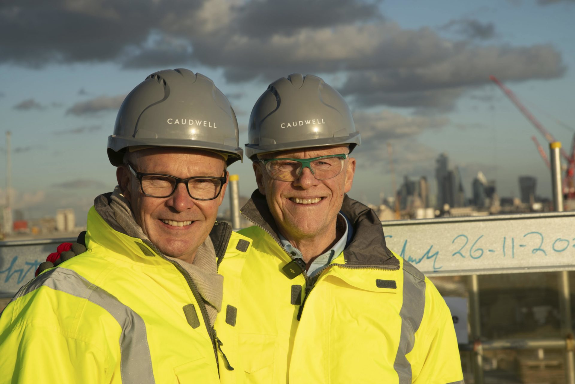 Richard Bosson and John Caudwell wearing hard hats and high-vis jackets smiling at the camera. 