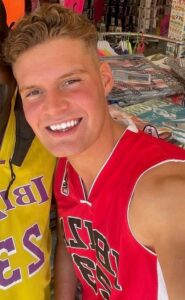 A young man with a basketball shirt smiling at the camera. His name is Liam MacDonald. He died after being crushed by a skip where BAM Nuttall was the contractor. The company has been fined £800k.