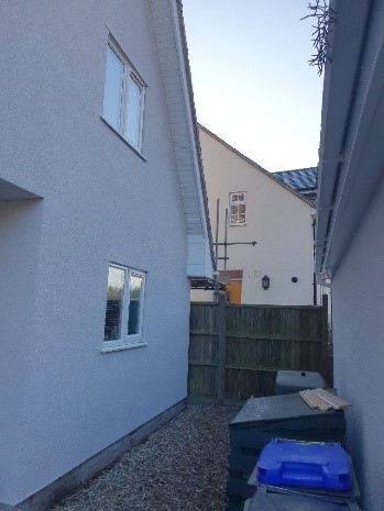 Side of a house with some bins against a wall. That's the spot where the worker fell from the roof. The company carrying out the works has been fined £120,000.