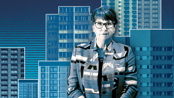 Dame Judith Hackitt wearing glasses and looking at the camera. On the background, there's a blue duotone montage of high-rises. In this article, industry professionals react to her latest warning at the Sir James Wates lecture.