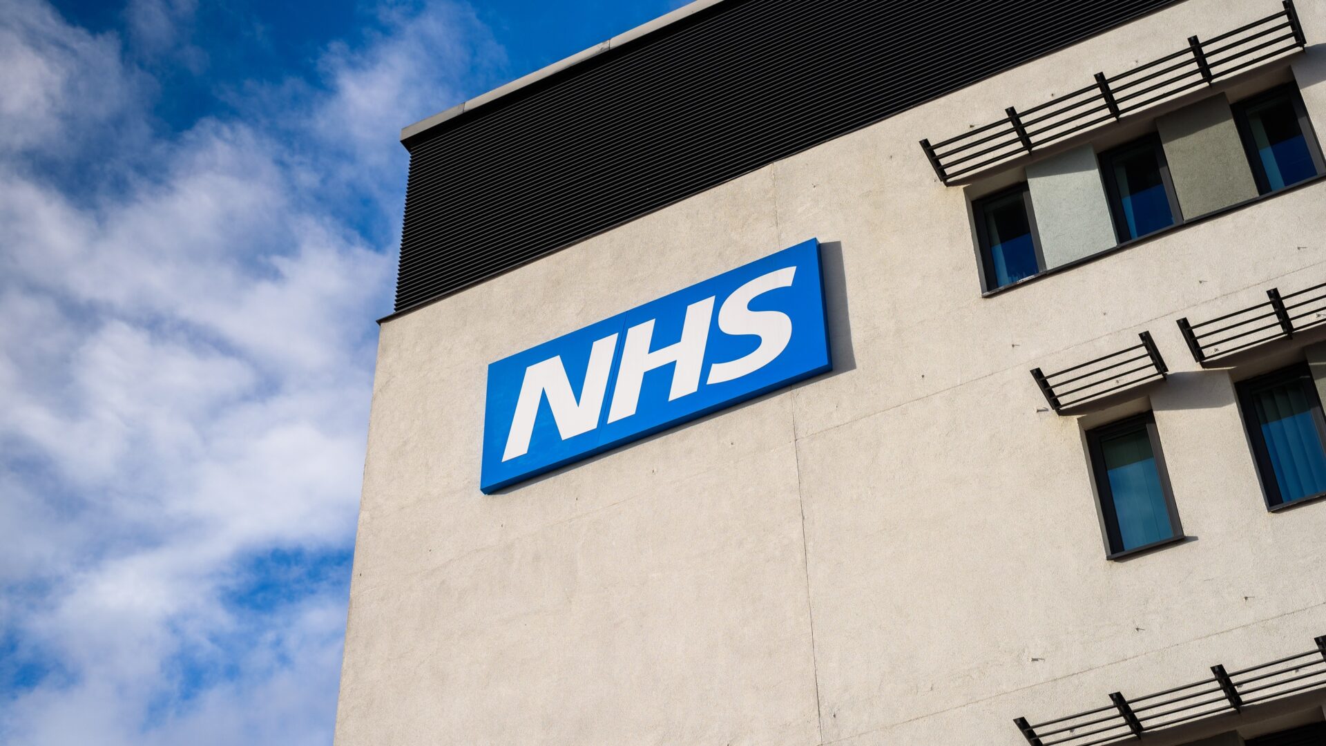 View of the NHS logo on a concrete building - Willmott Dixon and Kier are among the suppliers that have secured a place in a new NHS decarbonisation framework agreement.