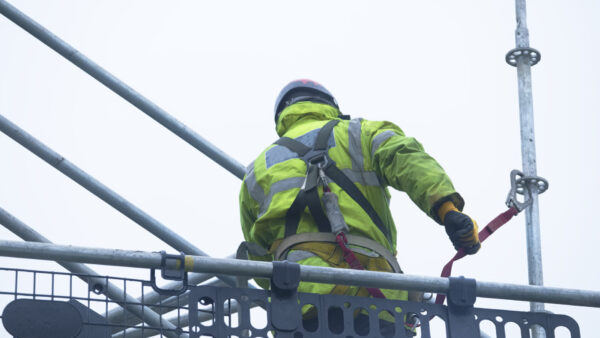 Construction worker dismantling access structure on construction building site