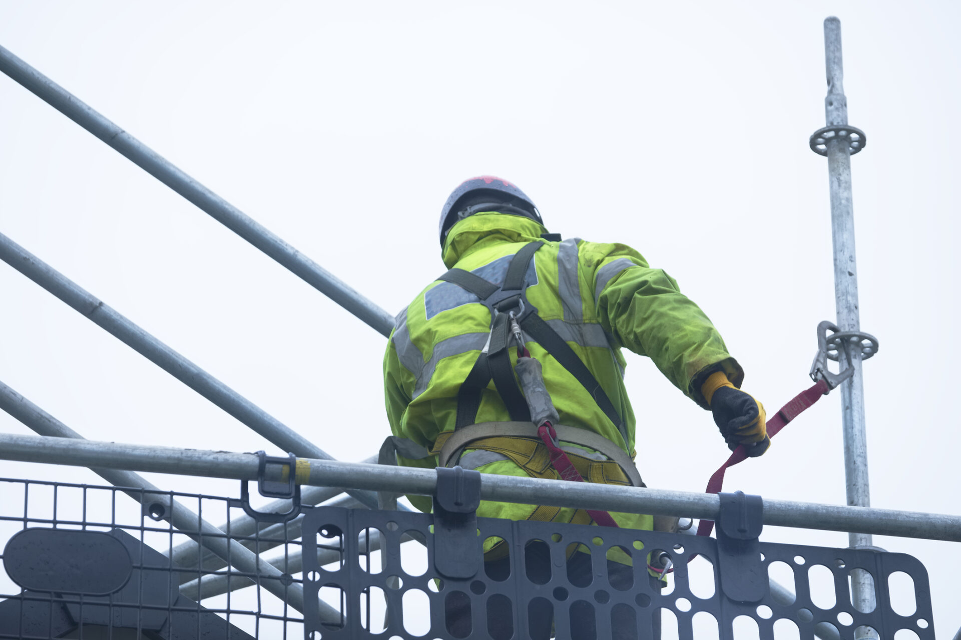 Construction worker dismantling access structure on construction building site 